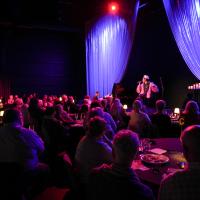 images of people at cabaret tables facing the stage with a performer signing 