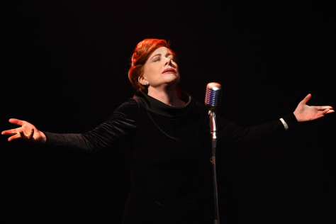 Bernadette Robinson with eyes closed, head tilted upwards and arms spread open